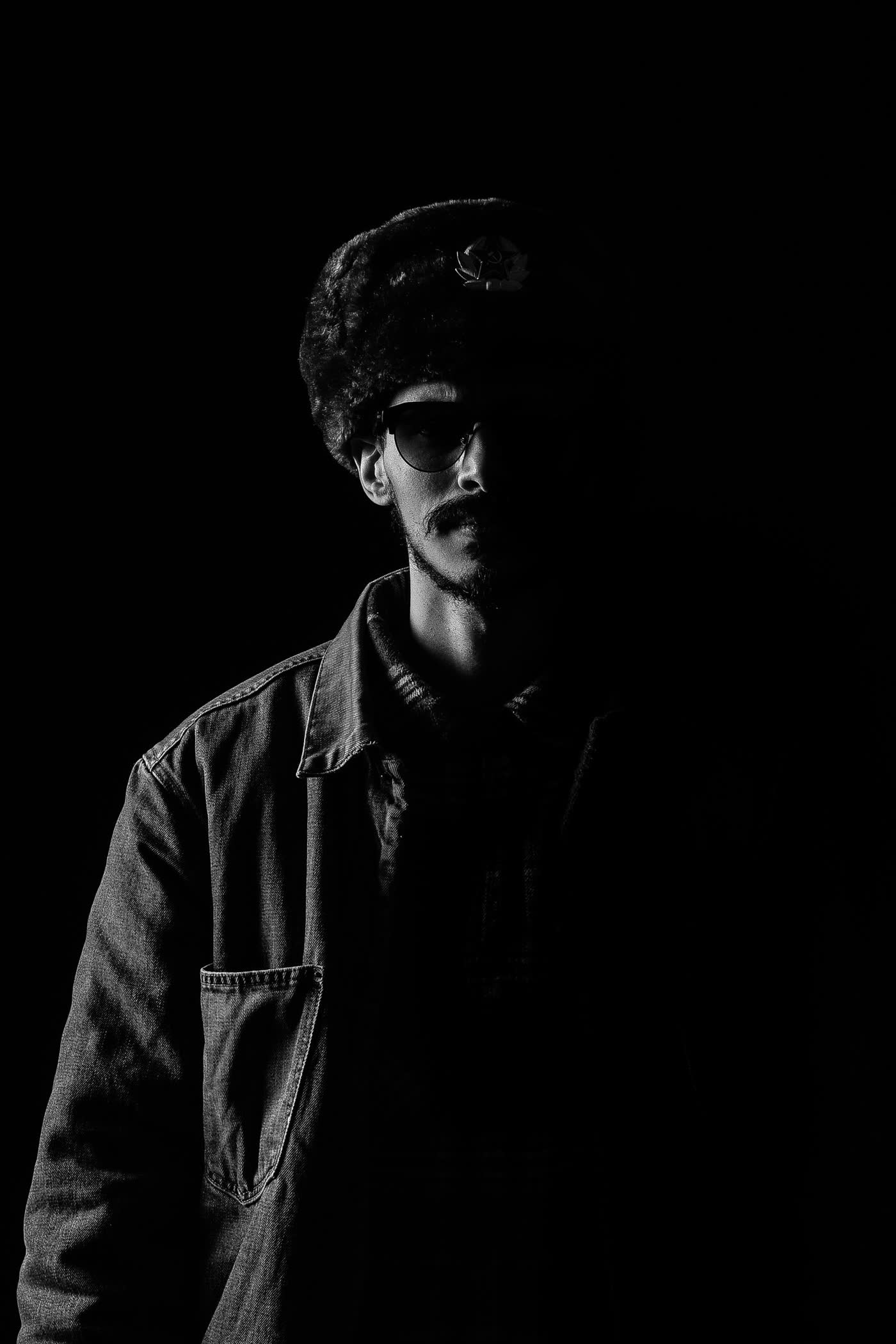 Black and white portrait of a man in a hat, deep shadow