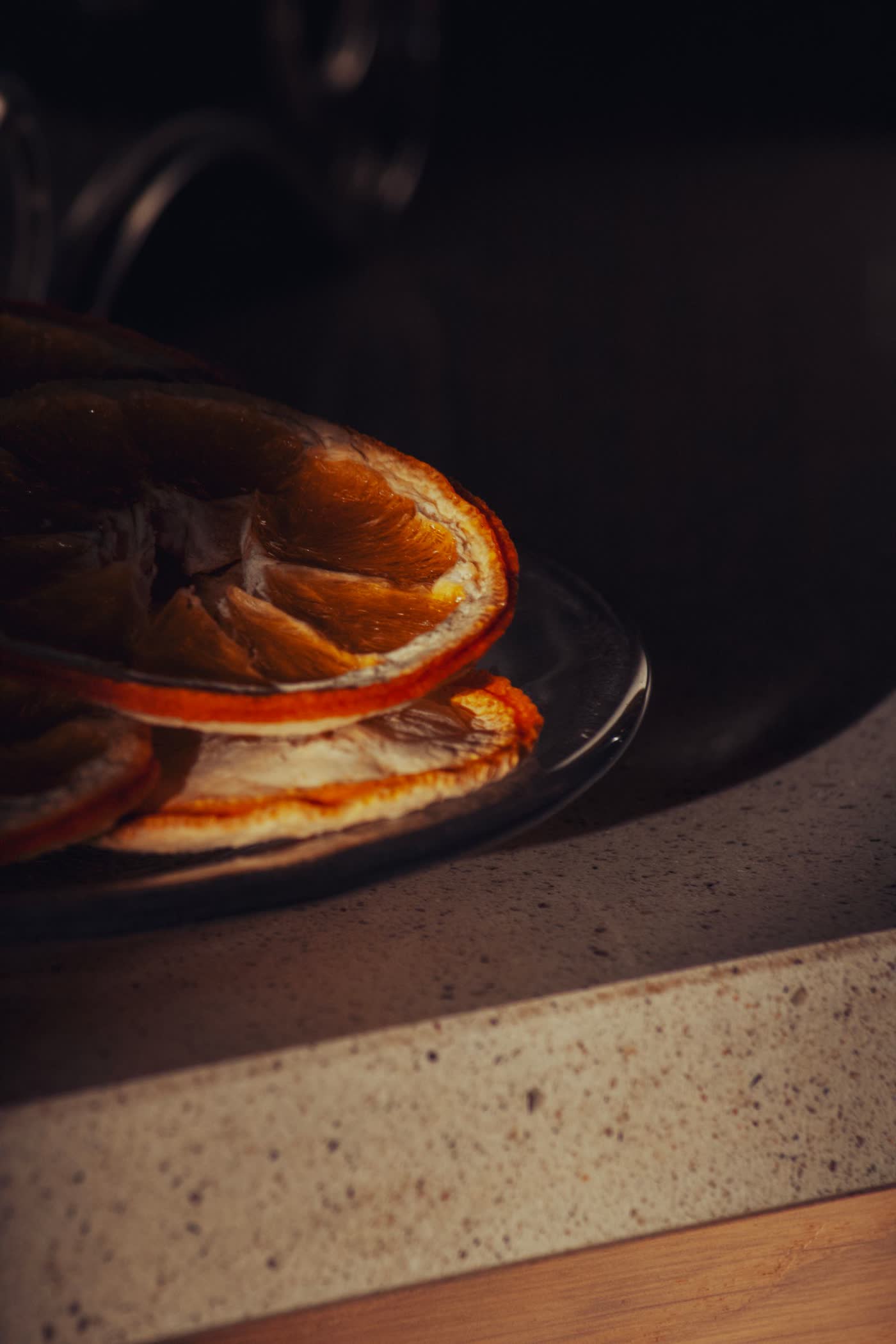Dried orange slices arranged on a dark plate, overhead still life