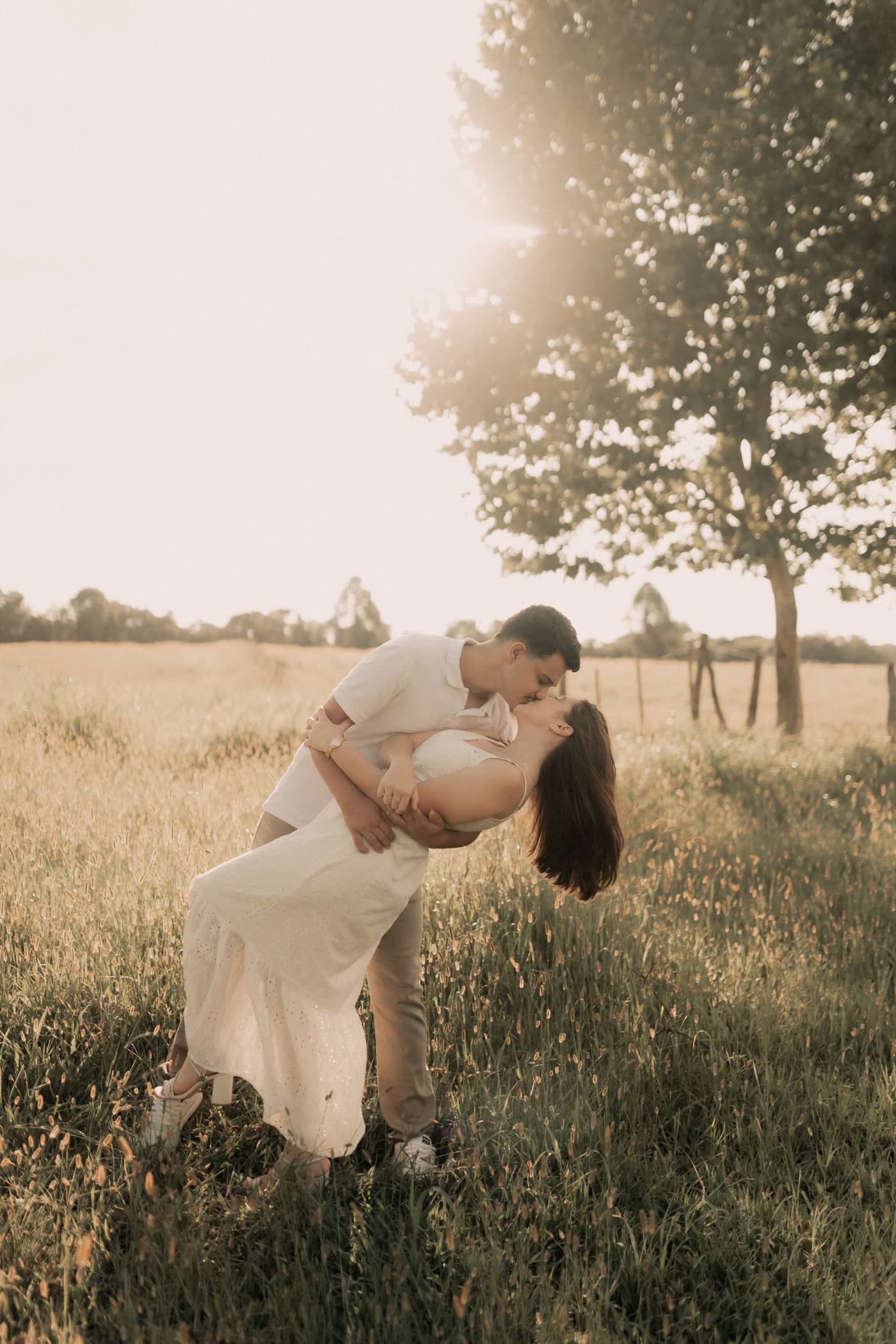 Couple dancing in a sunlit meadow at golden hour