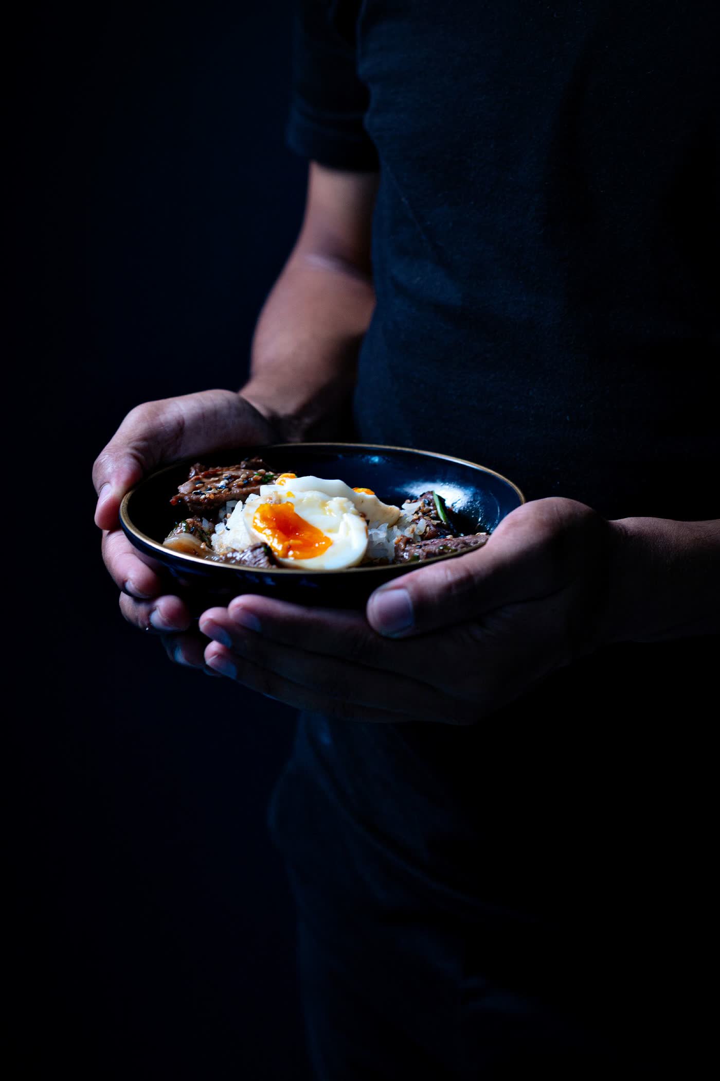 Dark food photograph of a poached egg dish, dramatic side light