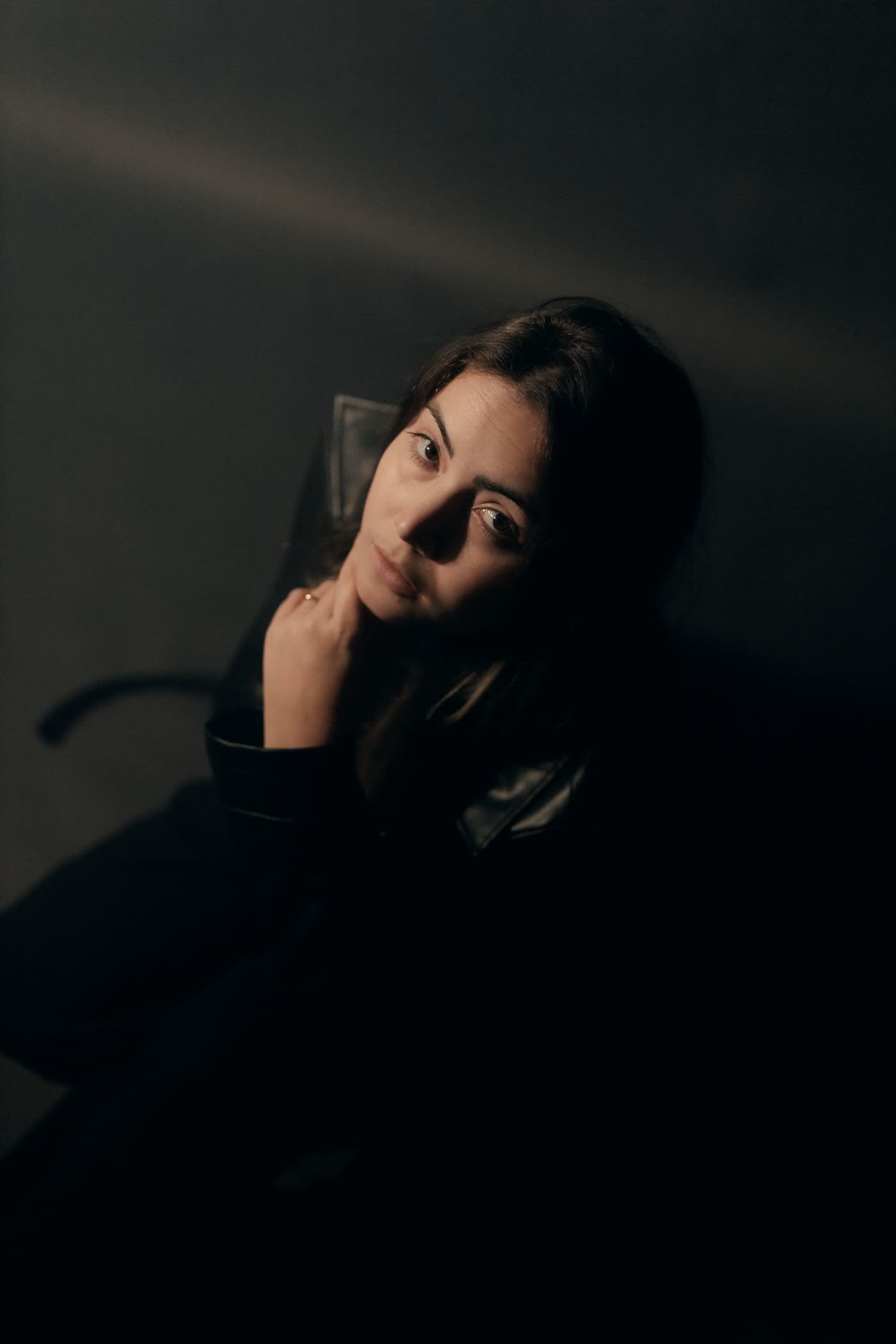 Moody portrait of a woman, warm key light on dark ground