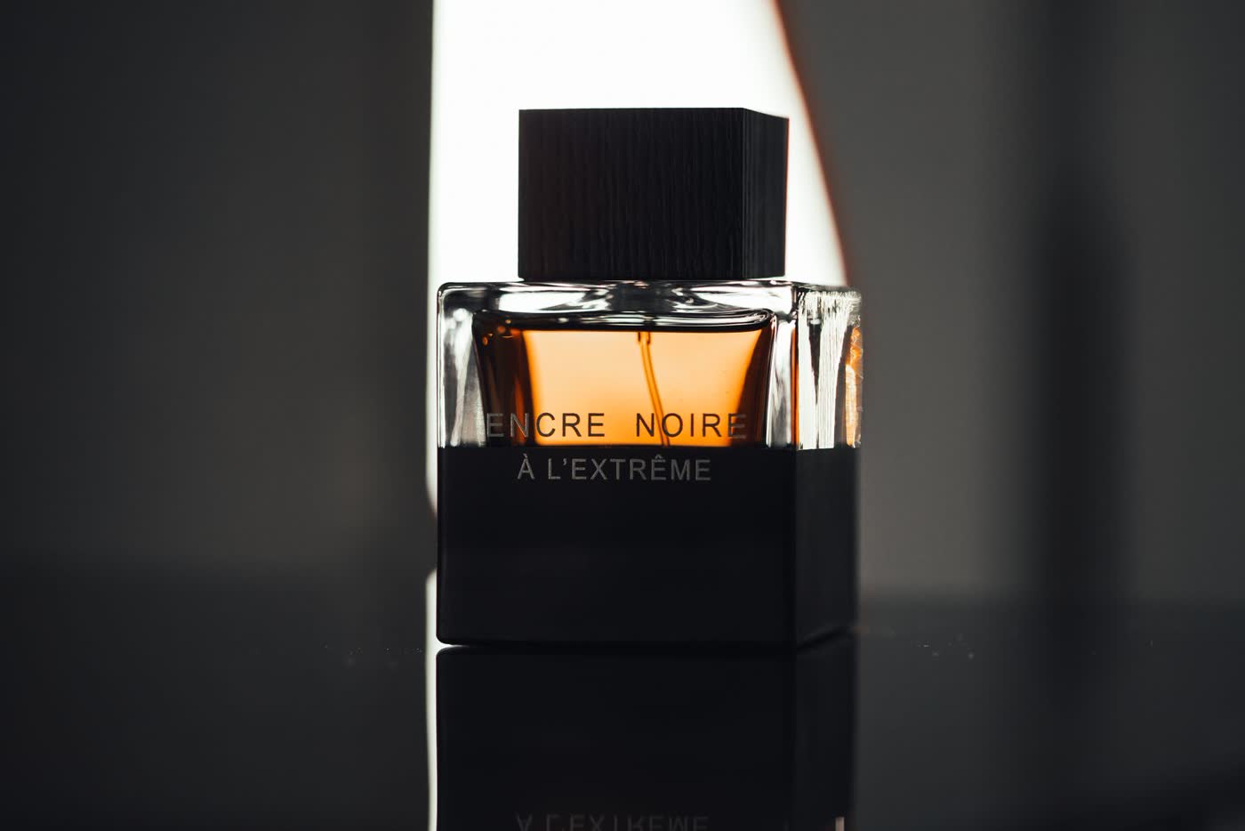 Black perfume bottle photographed on a dark reflective surface