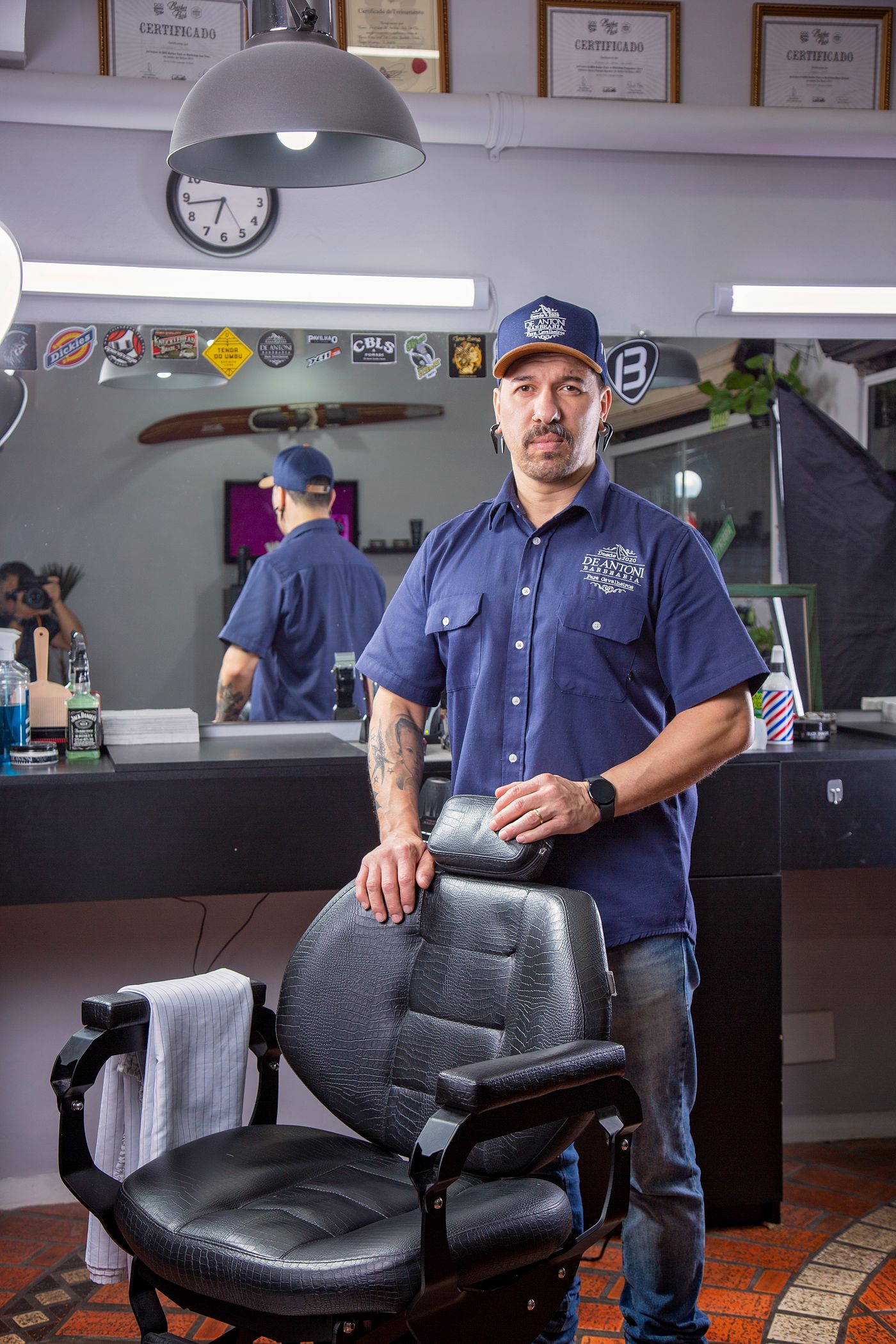 A barber standing beside his chair, waiting for the next customer.