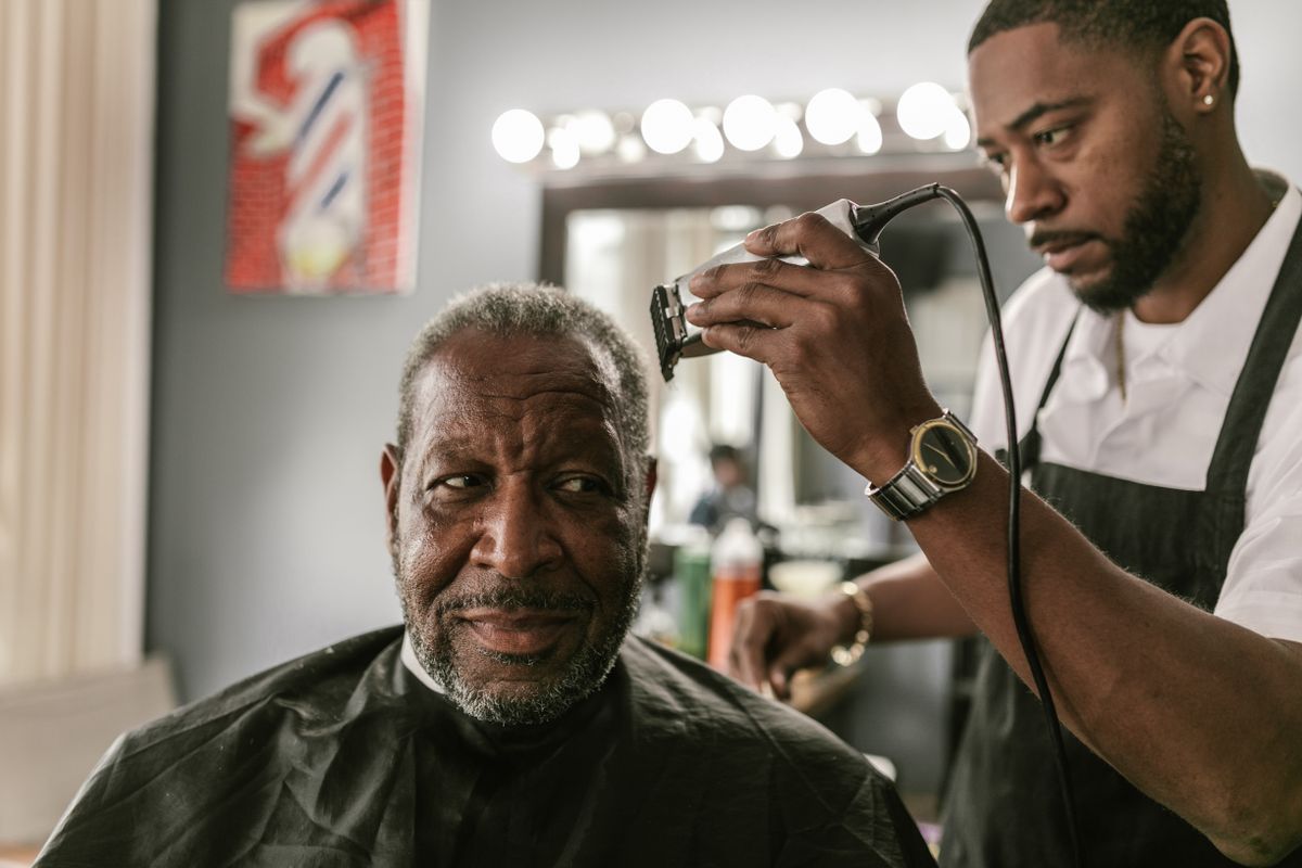 A beard being shaped and lined with trimmers.
