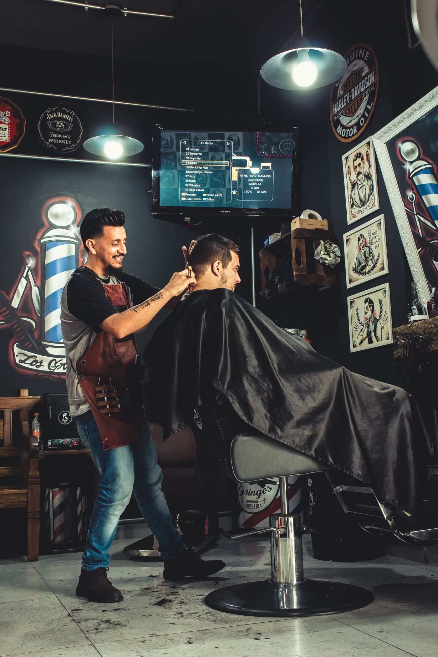 A barber part-way through a cut, comb and clippers in hand.